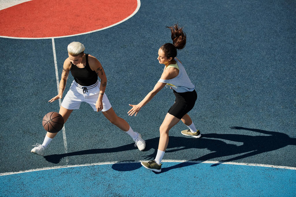 Dos jóvenes atléticas se levantan triunfalmente sobre una cancha de baloncesto bajo el sol del verano. - Foto, imagen