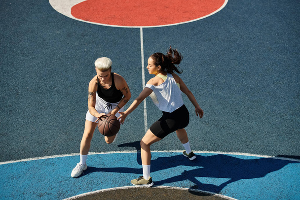 Twee atletische vrouwen staan vol vertrouwen op een basketbalveld, klaar om elke uitdaging aan te gaan die op hun pad komt.. - Foto, afbeelding