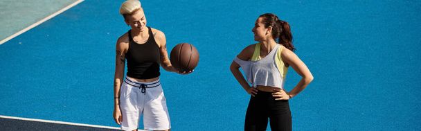 Twee atletische vrouwelijke vrienden staan trots op de top van een tennisbaan, koesteren in de zomer zonlicht. - Foto, afbeelding