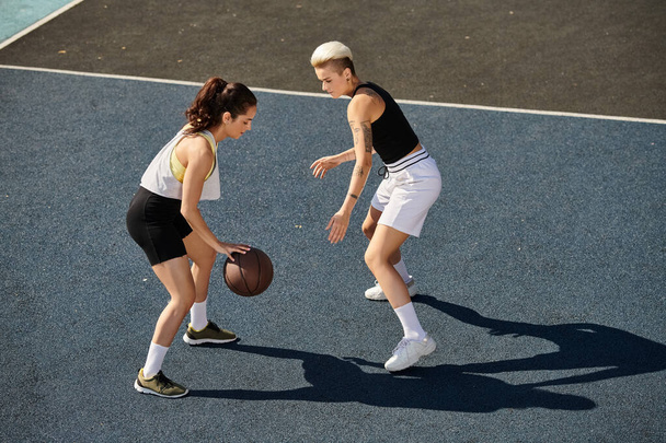 Δύο νεαρές αθλήτριες που παίζουν μπάσκετ σε υπαίθριο γήπεδο το καλοκαίρι. - Φωτογραφία, εικόνα