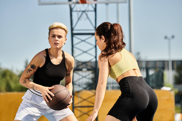 Dwie atletyczne koleżanki stojące obok siebie, trzymające koszykówkę na świeżym powietrzu latem. - Zdjęcie, obraz