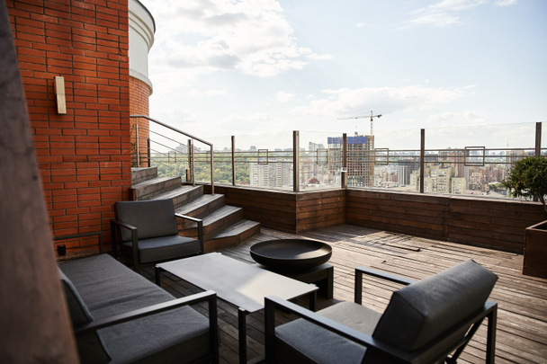 Затишний балкон з двома стільцями і столом, з видом на галасливий міський пейзаж знизу - Фото, зображення