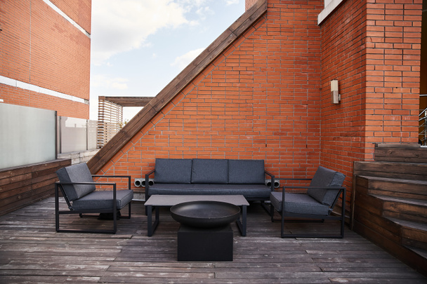 Tyylikäs patio, jossa mukava sohva, kutsuva tuolit, ja tyylikäs sohvapöytä asetettu taustaa vasten rauhallisuutta - Valokuva, kuva