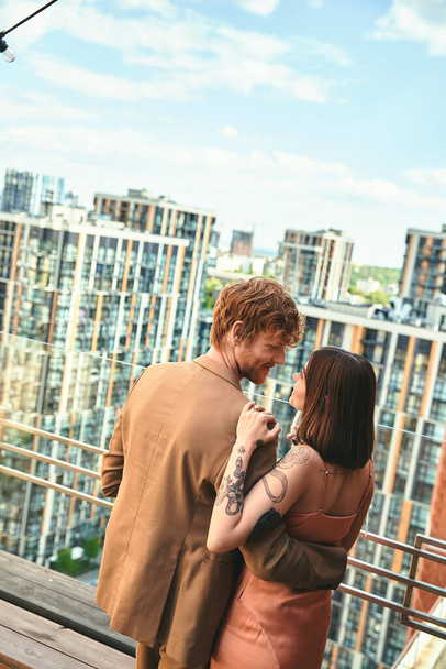 Um homem e uma mulher estão juntos em uma varanda, olhando para a vista em contemplação e desfrutando uns dos outros companhia - Foto, Imagem