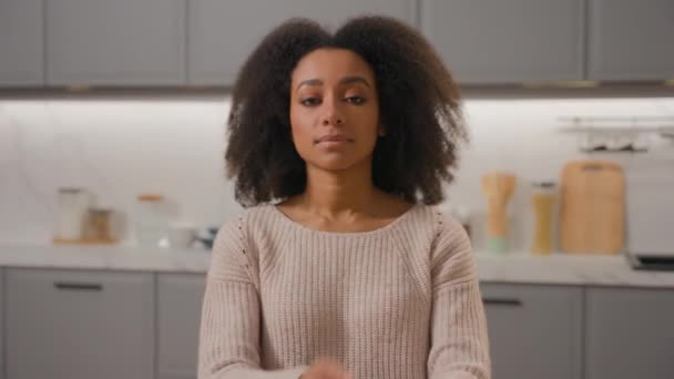 Afrikai amerikai etnikai lány magabiztos nő göndör haj hölgy kiadó lakás nézi kamera hazai konyha pózol keresztbe kézzel gyönyörű női háziasszony anya modell portré beltéri - Felvétel, videó
