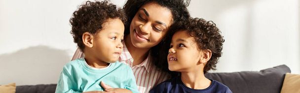 gioiosa donna afro-americana che abbraccia i suoi simpatici figlioletti che reggono il presente, festa della mamma, striscione - Foto, immagini