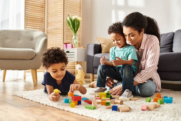 jolly beautiful african american woman playing with toys with her adorable little sons at home - Photo, Image