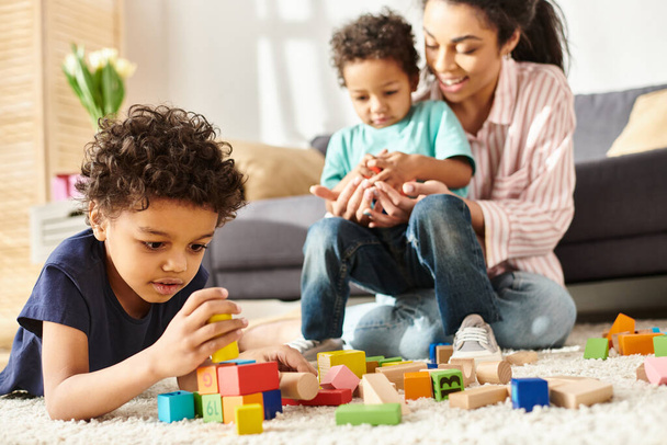foco en adorable afroamericano chico jugando con su borrosa madre y hermano en el telón de fondo - Foto, imagen