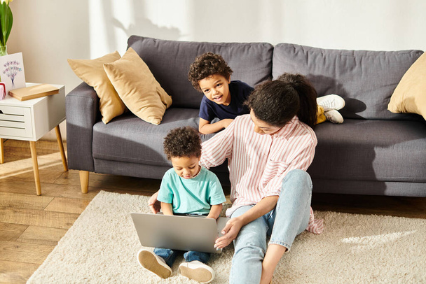 vreugdevolle Afrikaanse Amerikaanse moeder in homewear films kijken met haar schattige kleine zonen thuis - Foto, afbeelding