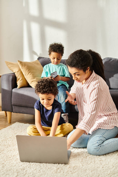 petit garçon afro-américain en utilisant le téléphone près de son frère et chère mère regardant ordinateur portable - Photo, image