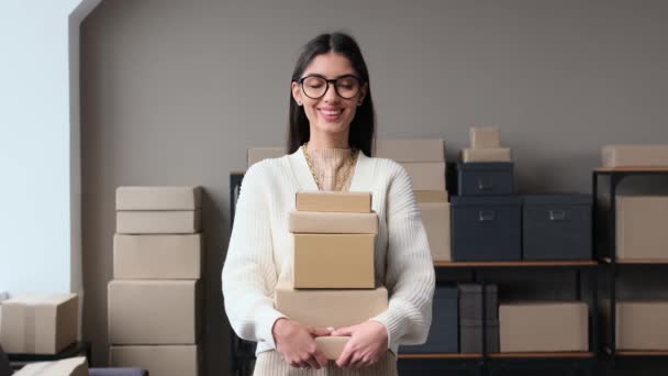 Portret pozytywnej białej kobiety przedsiębiorcy trzymającej skrzynki na paczki w magazynie. Właściciel sklepu internetowego, koncepcja handlu elektronicznego, logistyki i wysyłki. - Materiał filmowy, wideo