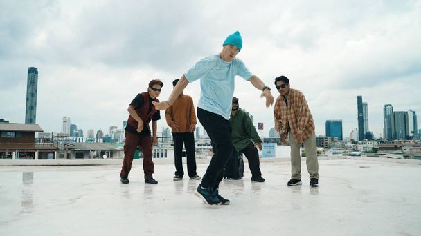 Professional break dance team practice B-boy dance while multicultural friends at rooftop. Young modern dancing group doing hip hop movement. Style,fashion,action. Outdoor sport 2024. Endeavor. - Photo, Image