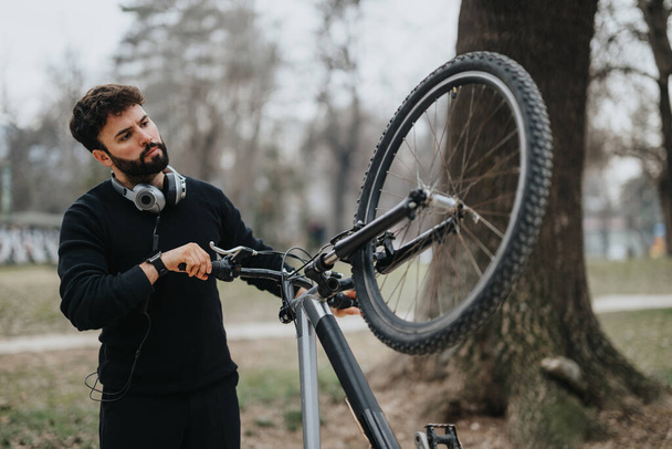 Ein professioneller Mann, der sich mit der Wartung seines Mountainbikes im Freien beschäftigt und eine Mischung aus Freizeit und Geschäft darstellt. - Foto, Bild