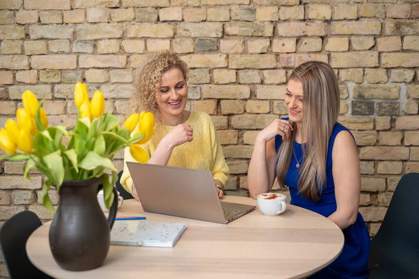Dos profesionales, la mujer, participan en una sesión de coaching, con un ordenador portátil y tulipanes vibrantes, discutiendo estrategias para el negocio y el crecimiento profesional. Foto de alta calidad - Foto, Imagen