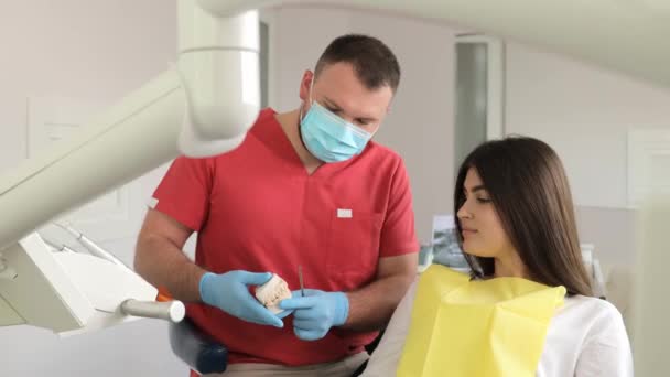 Mužský zubař mluví s mladou ženou sedící na zubním křesle. Moderní stomatologie. - Záběry, video
