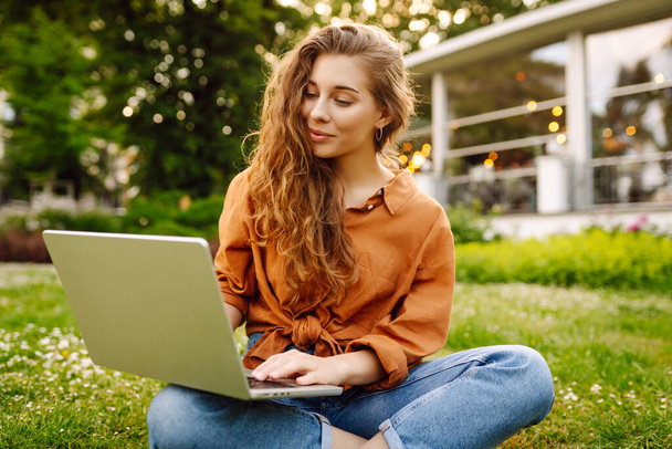 Pretty woman with laptop on the green grass. Education online. IT, Remote work. Business, blogging, freelance concept. - Photo, Image