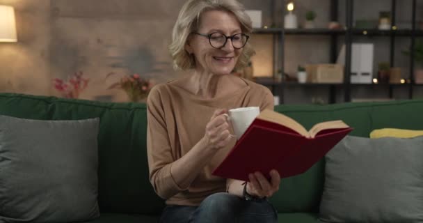 Eine reife kaukasische Frau liest zu Hause Buch und trägt eine Brille - Filmmaterial, Video