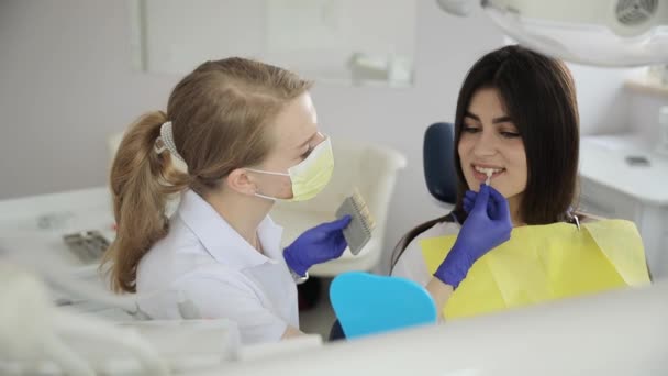 Žena v brýlích sedí v zubním křesle, zatímco zubař si prohlíží zuby. Usmívá se a radostně gestikuluje během volnočasové události. - Záběry, video