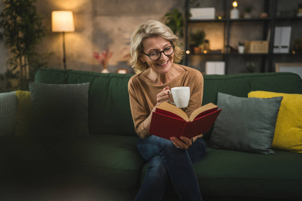Een vrouw volwassen Kaukasische vrouw lees boek thuis dragen bril - Foto, afbeelding