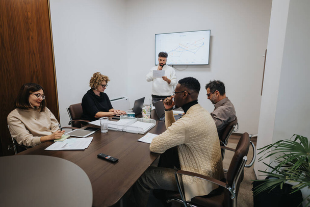 A diverse group of colleagues collaborating in a boardroom meeting, analyzing statistics and strategizing for business growth and profitability. - Photo, Image
