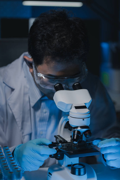 Een wetenschapper bestudeert steekproeven gebruikend een microscoop om het gebied van microbiologie te bestuderen en te ontwikkelen, worden de microscopen gebruikt door onderzoekers om chemotherapie te bestuderen. - Foto, afbeelding