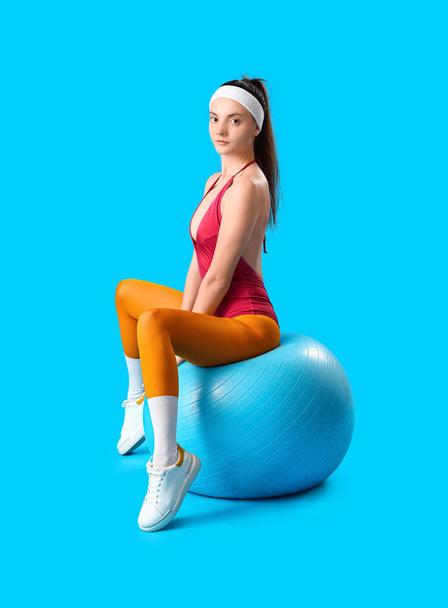 Αθλητική νεαρή γυναίκα με fitball σε μπλε φόντο - Φωτογραφία, εικόνα