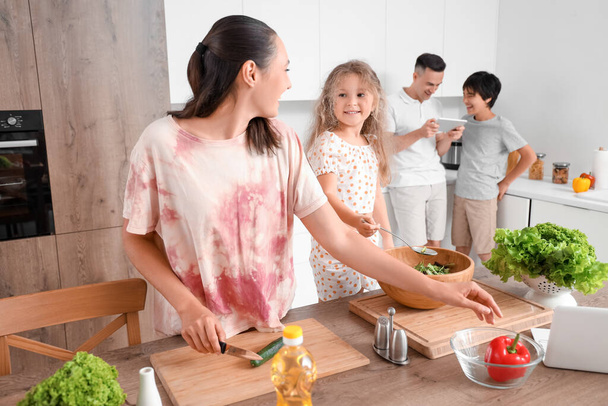 Onnellinen äiti pienen tyttärensä kanssa ruoanlaitto kasvissalaattia keittiössä - Valokuva, kuva
