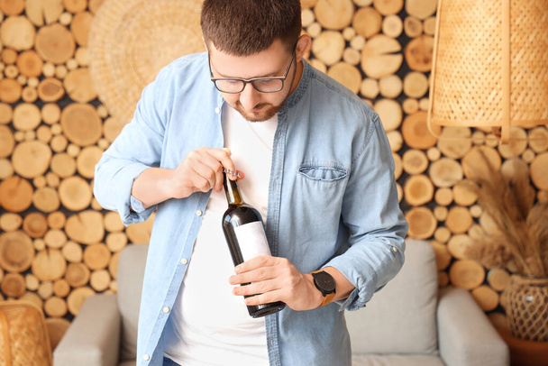 Sommelier öffnet Flasche Wein mit Korkenzieher im Wohnzimmer - Foto, Bild