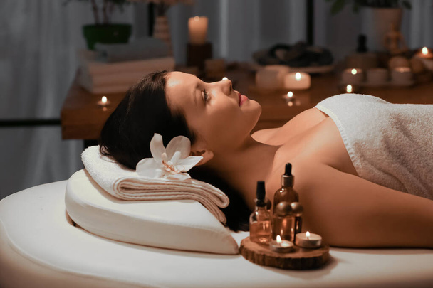 Mooie jonge vrouw ontspannen in donkere spa salon - Foto, afbeelding