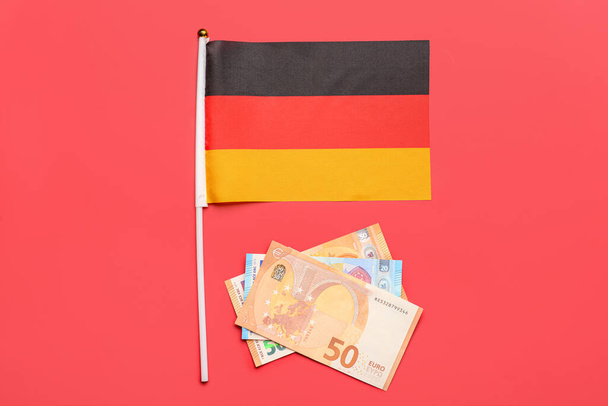 Bandera de Alemania y dinero sobre fondo rojo - Foto, Imagen
