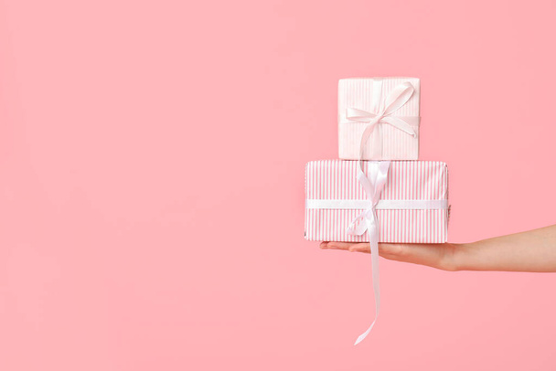 Vrouwelijke hand met geschenkdozen op roze achtergrond. Valentijnsdag - Foto, afbeelding