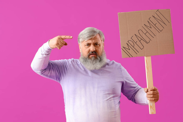 Protestujący dojrzały mężczyzna trzymający plakietkę ze słowem IMPEACHMENT na fioletowym tle - Zdjęcie, obraz