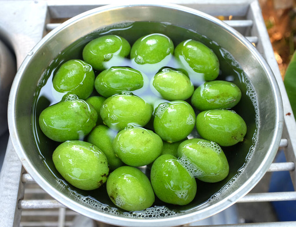νωπά πράσινα ωμά βιολογικά μάνγκο (Mangifera indica L. Var.) φρούτα σε ένα μπολ με νερό στο τραπέζι top.food έννοια διατήρηση των φρούτων για μεγάλο χρονικό διάστημα, κομπόστα φρούτων, μάνγκο τουρσί  - Φωτογραφία, εικόνα
