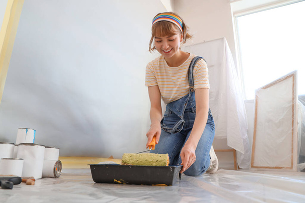 Nuori nainen maalaustela tekee korjaus huoneessa - Valokuva, kuva