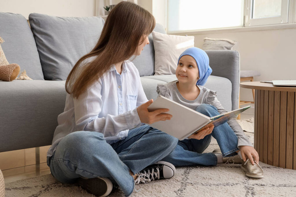 Κοριτσάκι μετά τη χημειοθεραπεία με τη μητέρα της να διαβάζει ιστορία στο σπίτι. Διεθνής Ημέρα κατά του καρκίνου της παιδικής ηλικίας - Φωτογραφία, εικόνα