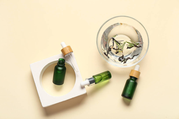 Samenstelling met flessen etherische olie en glas water op kleur achtergrond - Foto, afbeelding