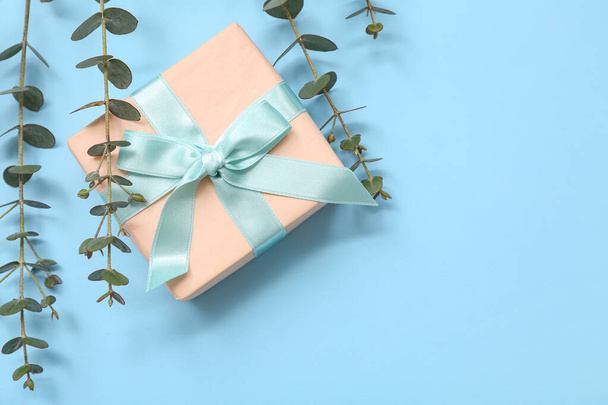 Caja de regalo y eucalipto sobre fondo azul. Día Internacional de la Mujer - Foto, imagen