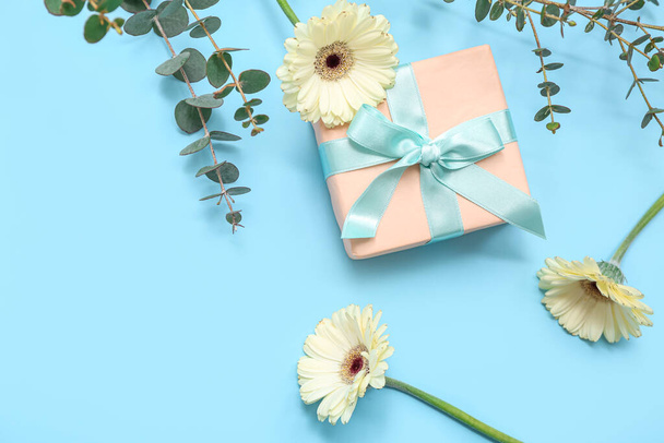 Confezione regalo con bellissimi fiori di gerbera ed eucalipto su sfondo blu. Giornata internazionale della donna - Foto, immagini