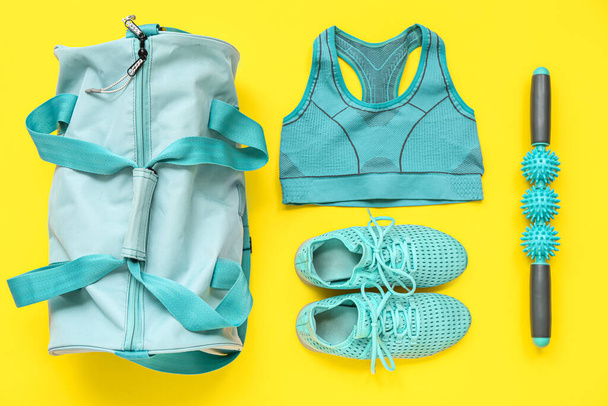 Sporttasche mit Sportbekleidung und Trainingsgeräten auf gelbem Hintergrund - Foto, Bild