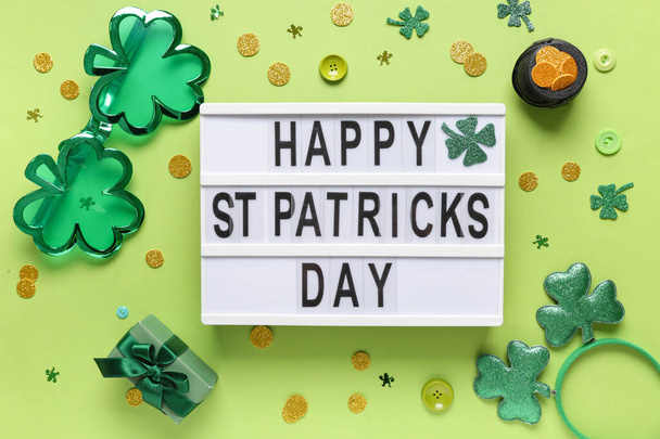 Board with words HAPPY ST PATRICKS DAY, plastic eyeglasses and decor on green background - Photo, Image