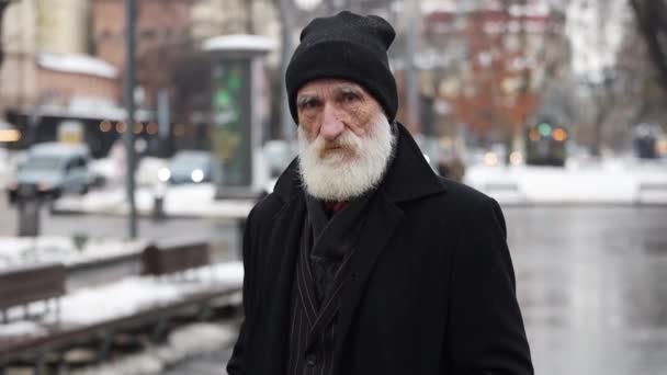 Портрет старого зморщеного бородатого чоловіка, що стоїть у місті і дивиться на камеру. Продуманий, сумний старий самотній дід. - Кадри, відео