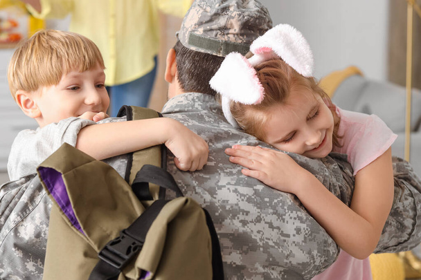 Маленькі діти обіймають свого військового батька вдома на Великдень, вид ззаду - Фото, зображення