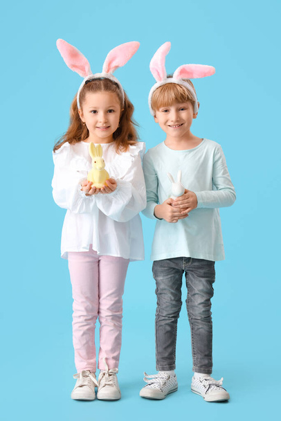 Aranyos kisgyerekek nyuszifül játékokkal nyúl kék háttér. Húsvéti ünnepség - Fotó, kép