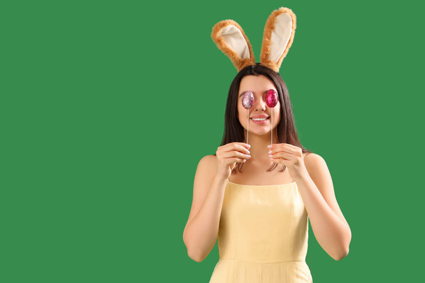 Gyönyörű fiatal nő nyuszifül húsvéti tojás zöld háttér - Fotó, kép