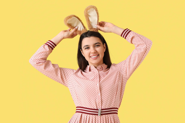 Красива молода жінка в вухах кролика на жовтому тлі. Великоднє святкування - Фото, зображення