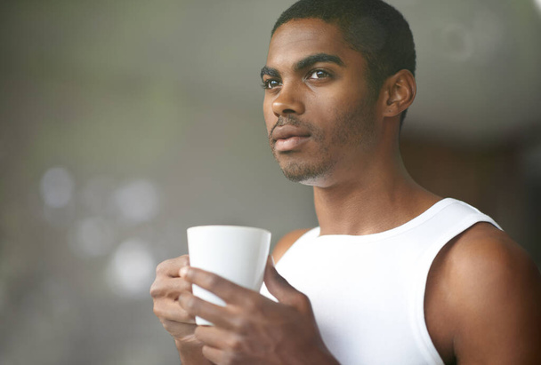 Homme noir, pensant et matin avec café pour le petit déjeuner début ou ambition sur fond bokeh à la maison. Visage de jeune Africain ou d'homme émerveillé, réfléchi ou détendu avec une tasse, une tasse ou un thé à la maison. - Photo, image