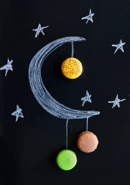 Illustration artistique d'un croissant de lune fait de craie avec de délicieux macarons suspendus, symbolisant un événement céleste avec une touche de douceur - Photo, image