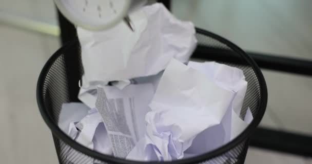 Tijd en de werknemer verwerpt nieuwe ideeën met veel papierwerk. Alarm klok met papieren documenten projecten in prullenbak - Video