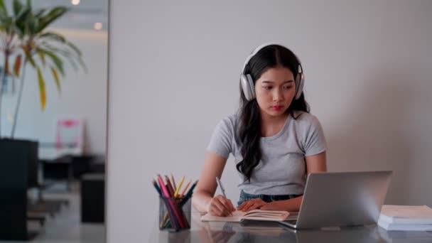 Az ázsiai tinédzser lány a végzős éveiben laptopot használ tanulási anyagok kutatására és összegzésére egy kávézóban. Kiváló minőségű 4k felvételek - Felvétel, videó