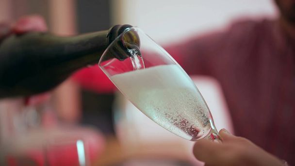 Serving champagne into glass close-up. Pouring celebratory drink during holidays - Photo, Image